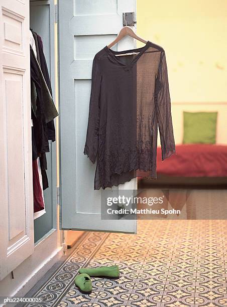 open closet with blouse hanging from door. - door stockfoto's en -beelden
