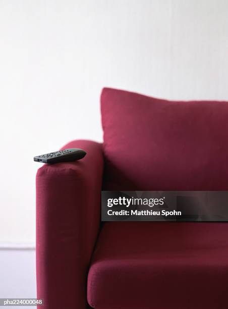 remote control sitting on couch arm, partial view. - armlehne stock-fotos und bilder