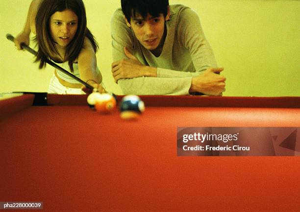 young couple playing billiards, waist up, billiard table in foreground. - being watched stockfoto's en -beelden