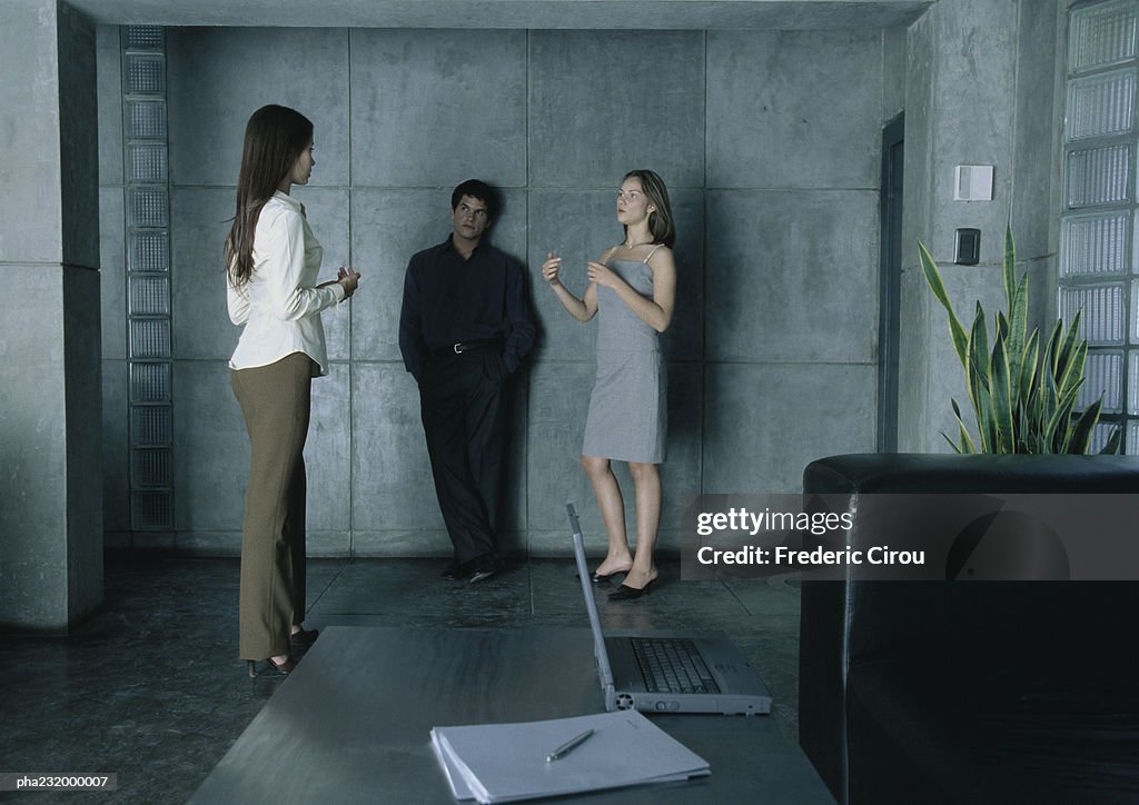 Woman talking to woman standing next to man.