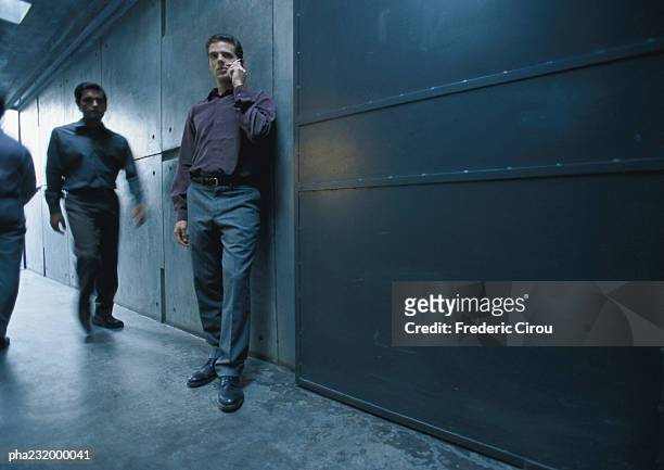 men standing in hallway, one on cell phone. - industrial doors stock pictures, royalty-free photos & images