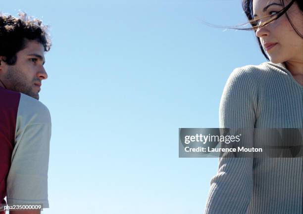 man and woman looking at each other with sky in background. - sospetto foto e immagini stock