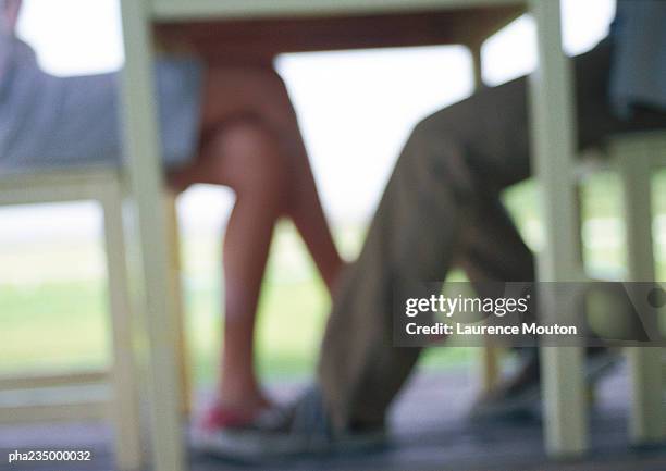 man and woman sitting at table, silhouette blurred,  focus on feet. - playing footsie stock pictures, royalty-free photos & images