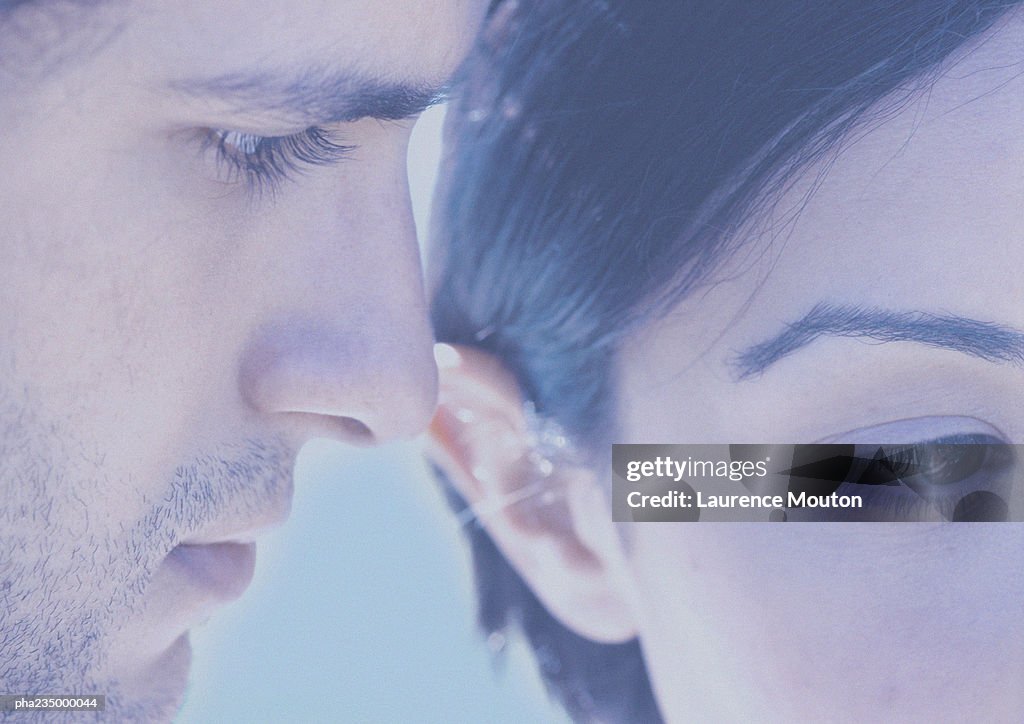 Man and woman with faces next to each other, close up, blurred, faded.