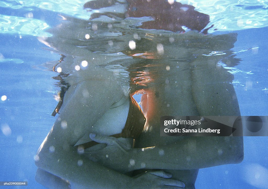 Couple embracing, mid-section, underwater view