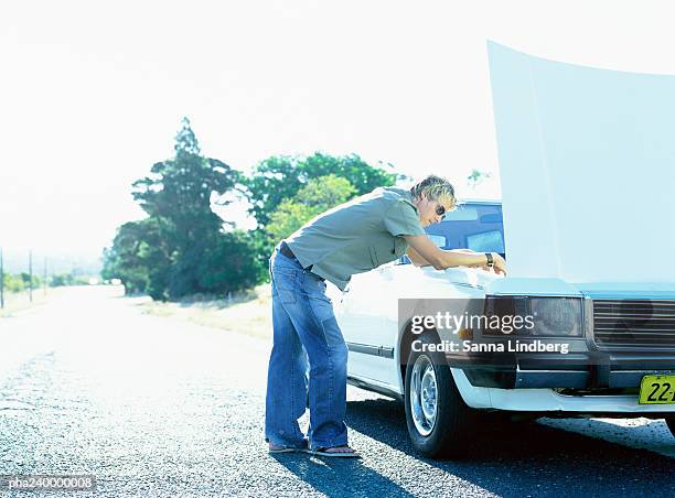 man looking under car hood - vehicle breakdown ストックフォトと画像