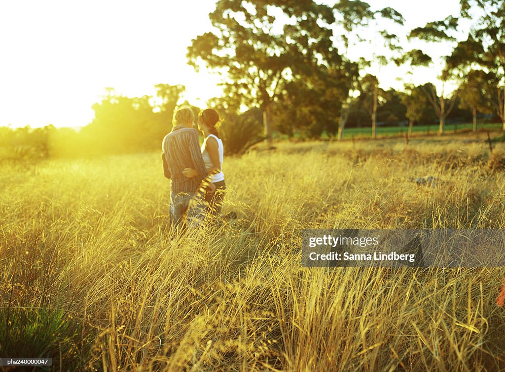 Couple in field of tall grass, rear view