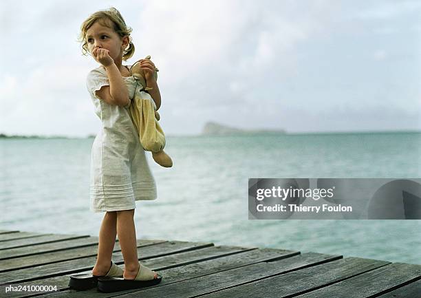 little girl standing on dock, sucking thumb and looking over shoulder - girl looking over shoulder stock pictures, royalty-free photos & images