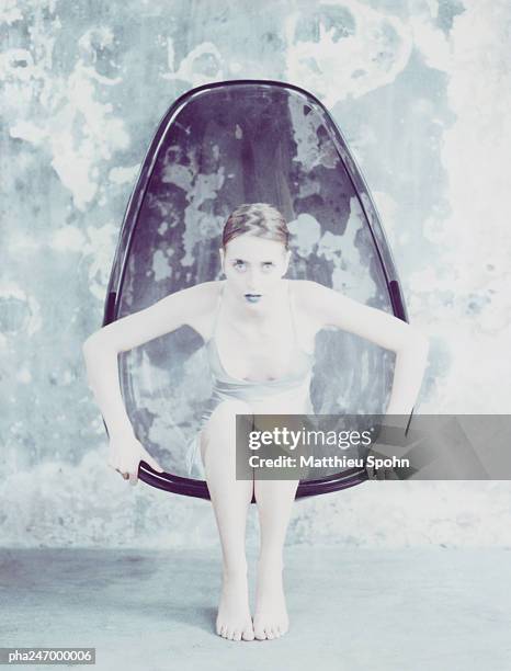 woman sitting in egg-shaped chair - egg chair stockfoto's en -beelden