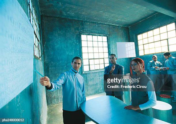 group of people in a room, man pointing at screen on wall - being watched stockfoto's en -beelden
