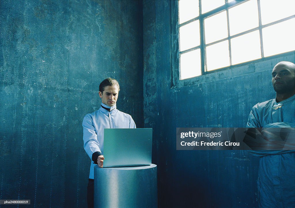 Man using laptop computer, man folding arms