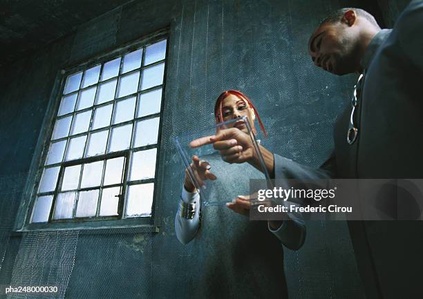 man and woman looking at pane of glass - beobachtung stock-fotos und bilder