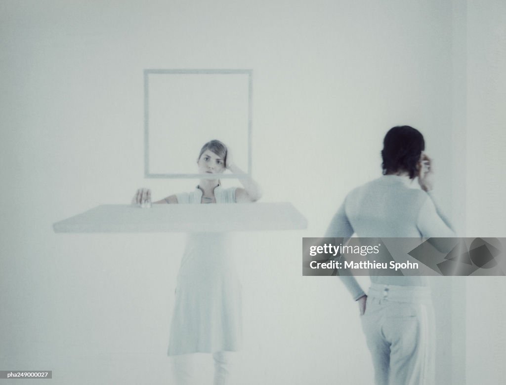 Woman behind square frame, man holding cell phone