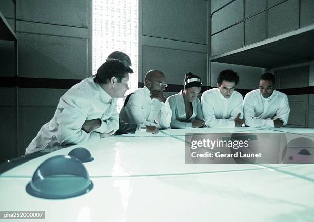 people standing around table - being watched stockfoto's en -beelden