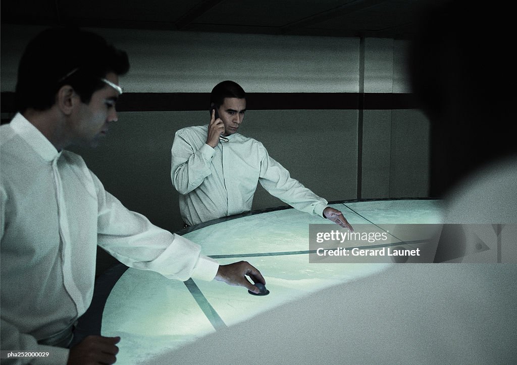 Man using cell phone, man moving object on round table