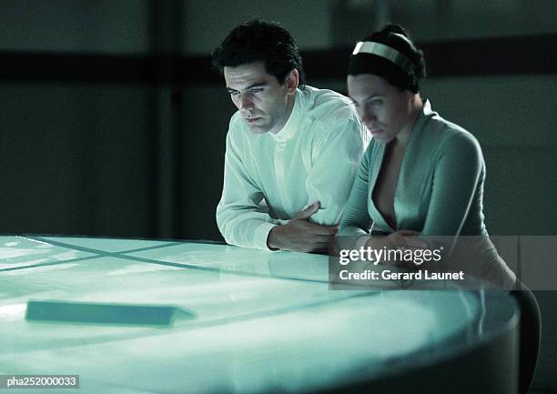 man and woman leaning on round table - beobachtung stock-fotos und bilder