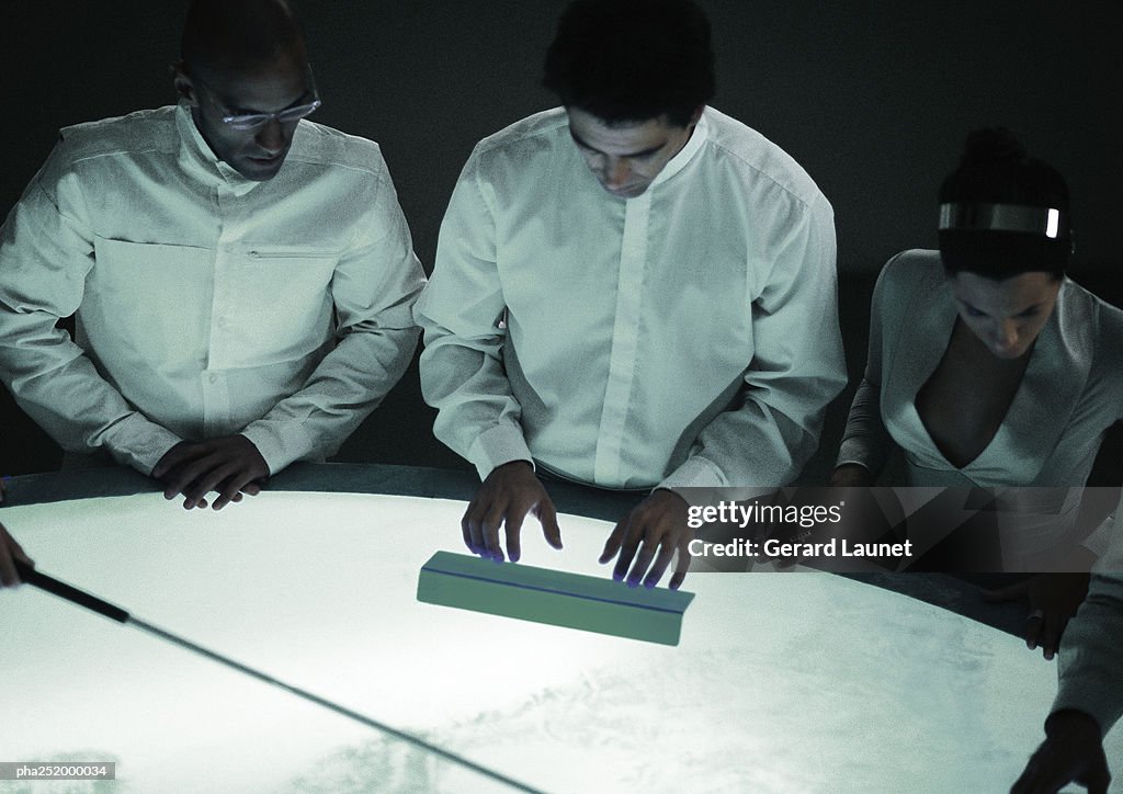 Three people with hands on table, high angle view