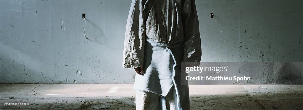 Person standing in front of wall, mid-section