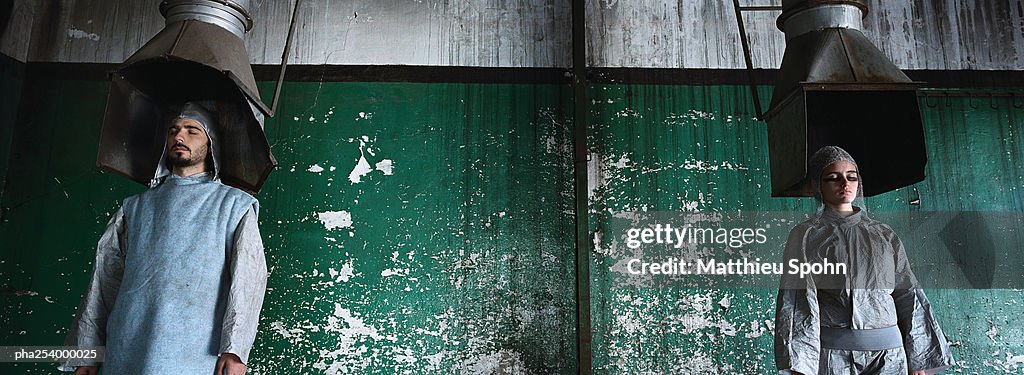 Man and woman standing under pipes