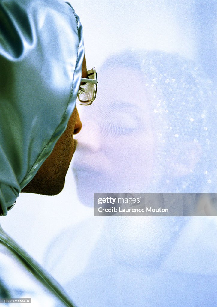 Man and woman standing on each side of transparent screen