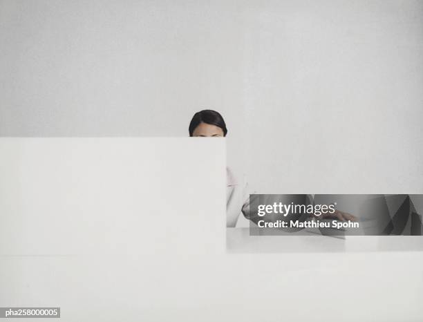 woman sitting behind desk, face hidden, with hand on pile of books - intersected stock pictures, royalty-free photos & images