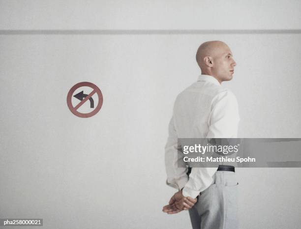 man standing with hands behind back with back turned to no left turn sign - no stock pictures, royalty-free photos & images