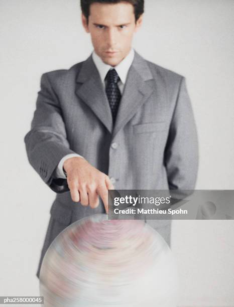 man in suit standing with finger on globe - world at your fingertips stockfoto's en -beelden