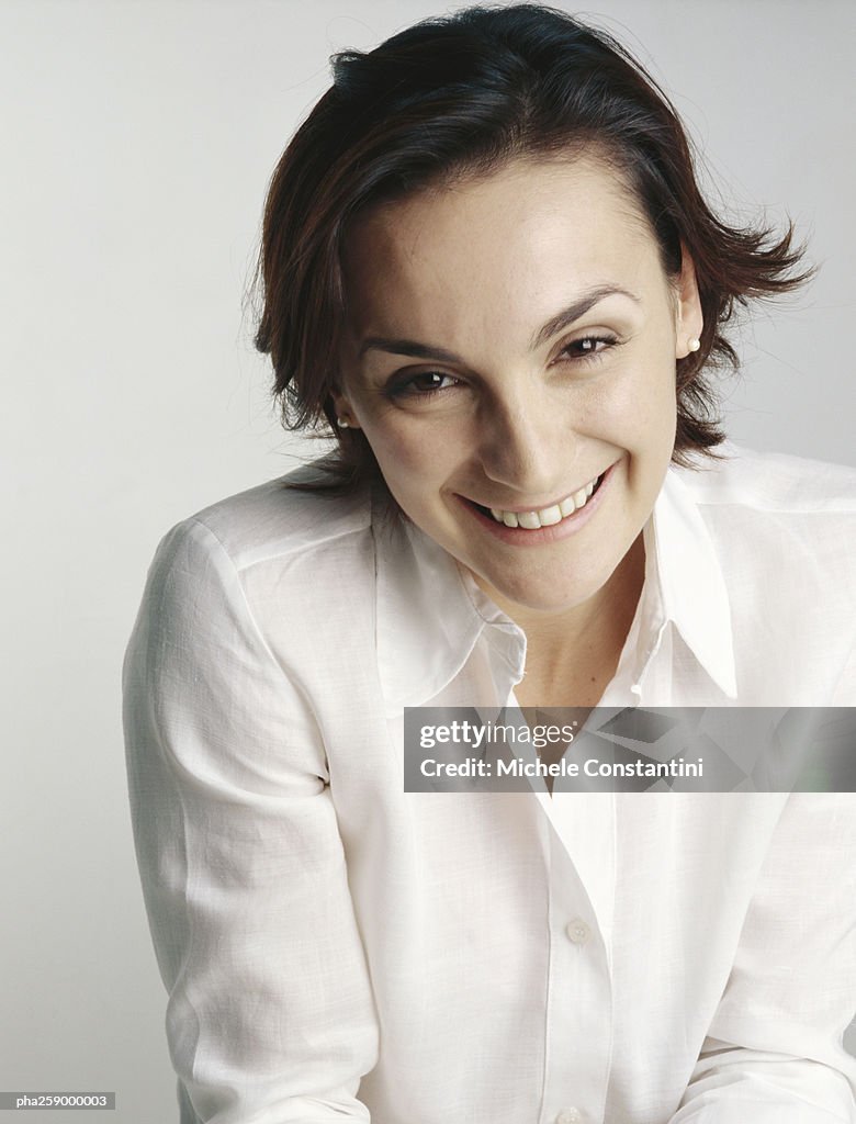 Young woman smiling at camera with eyebrows raised and head slightly tilted forward