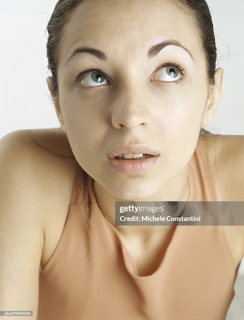 Young woman looking up with raised eyebrows, close-up