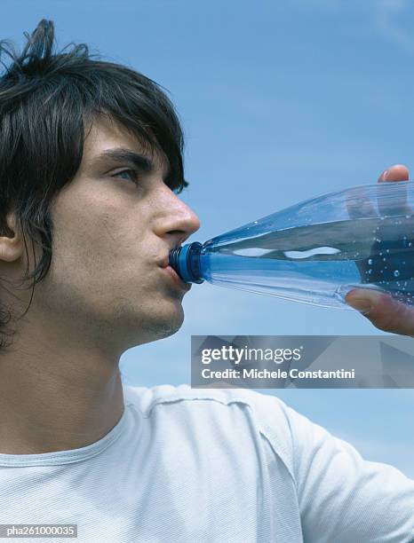 young man drinking from bottle, looking out of frame, close-up - out of frame stock pictures, royalty-free photos & images