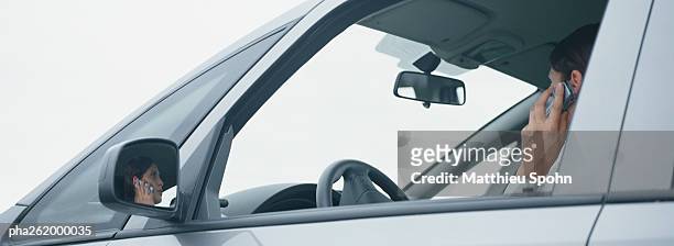 woman in car talking on cell phone, reflection in rear view mirror - reflection foto e immagini stock
