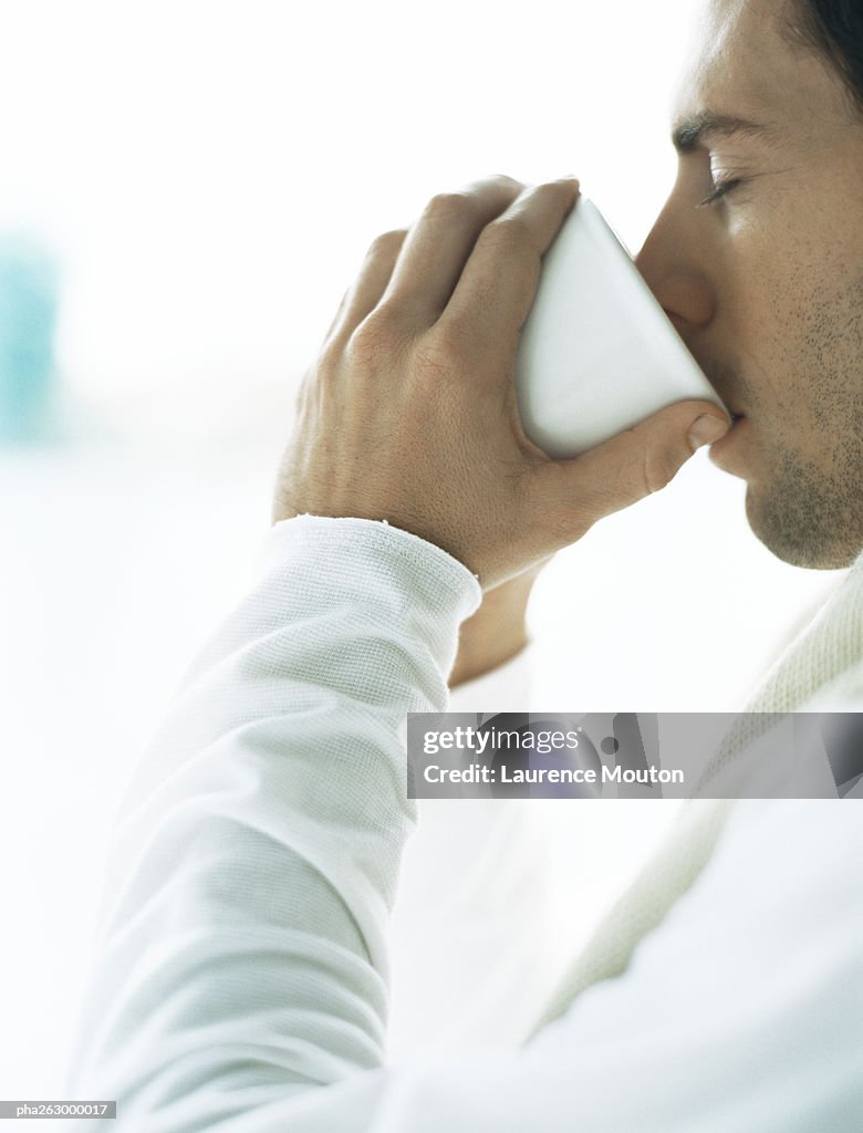 Man drinking from cup, eyes closed