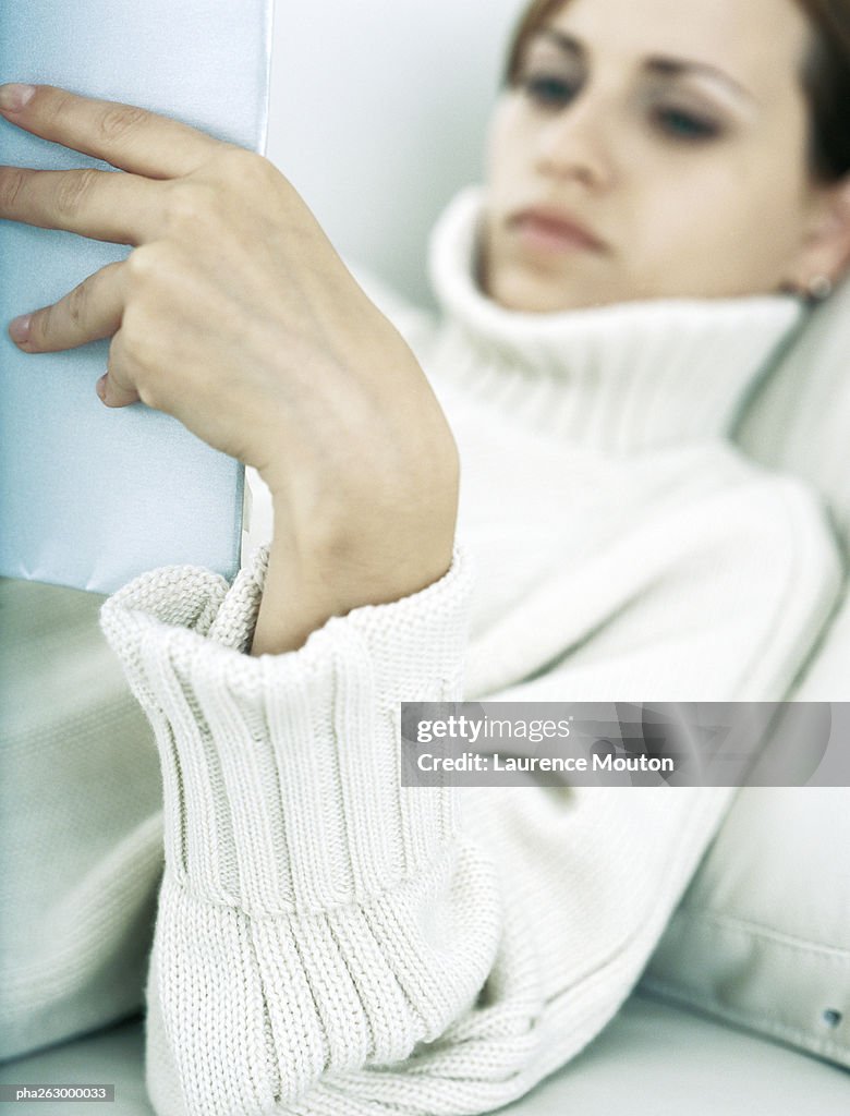 Woman lying back on pillow holding up book