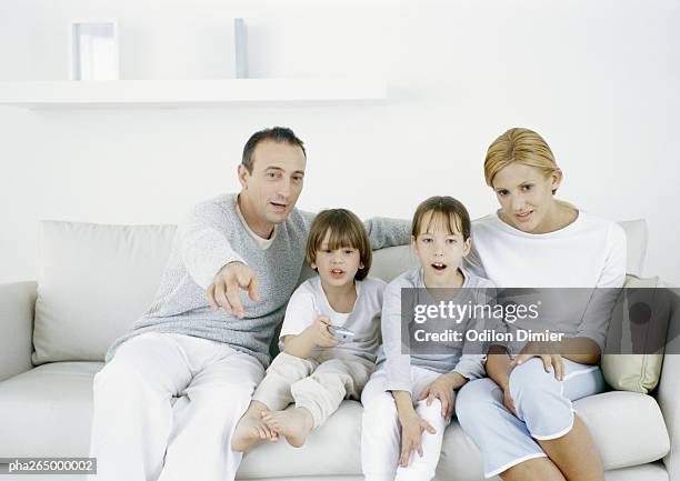 parents with sitting on sofa with daughter and son, father pointing straight ahead - ahead stock pictures, royalty-free photos & images