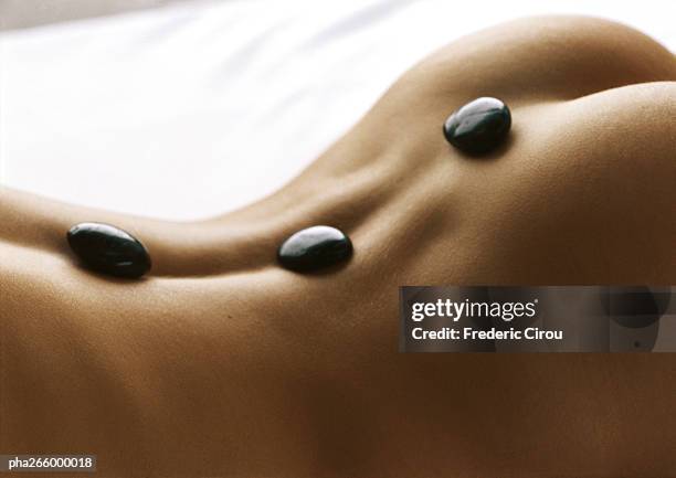 woman's bare back with black stones on spine, close-up - spagat stockfoto's en -beelden