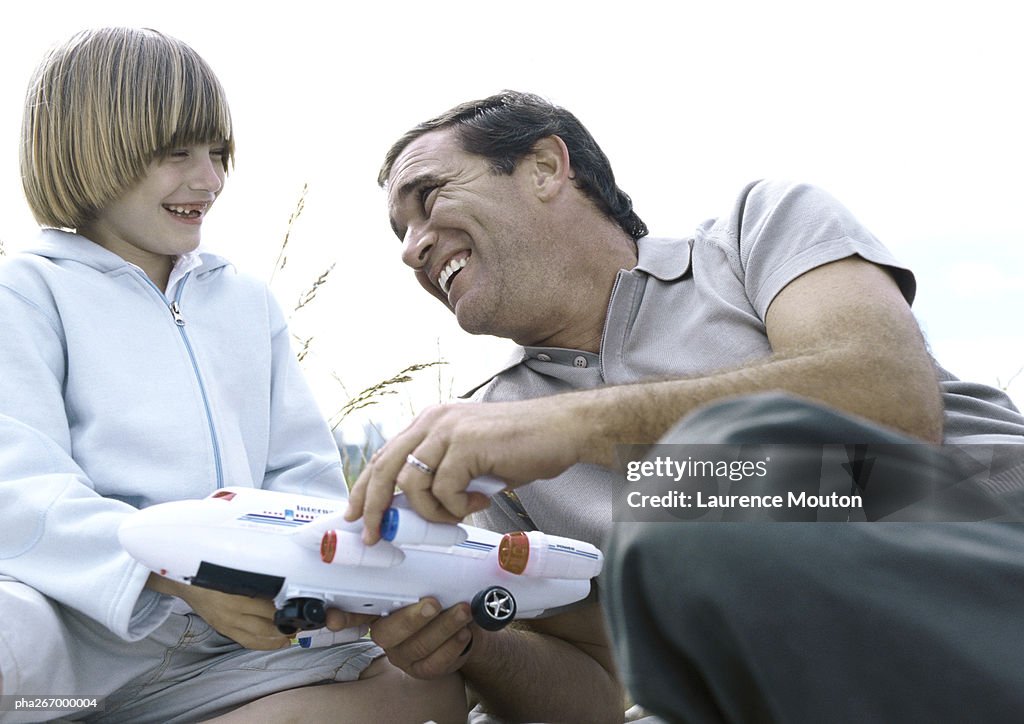 Father and son holding toy plane