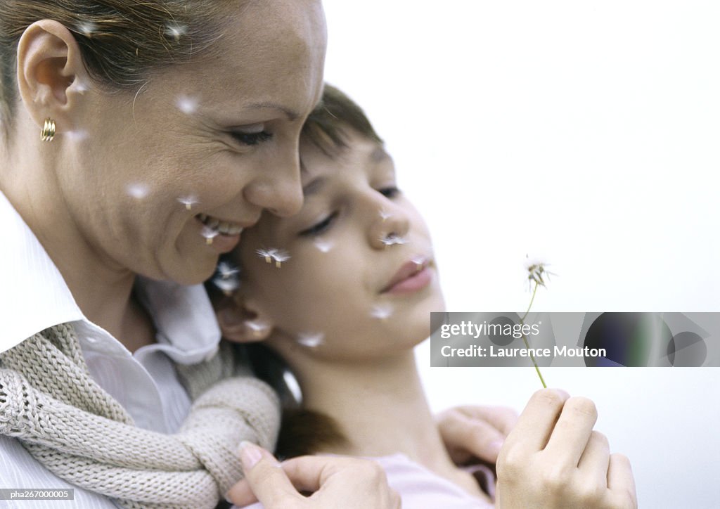 Mother with girl blowing dandelion seeds, close-up