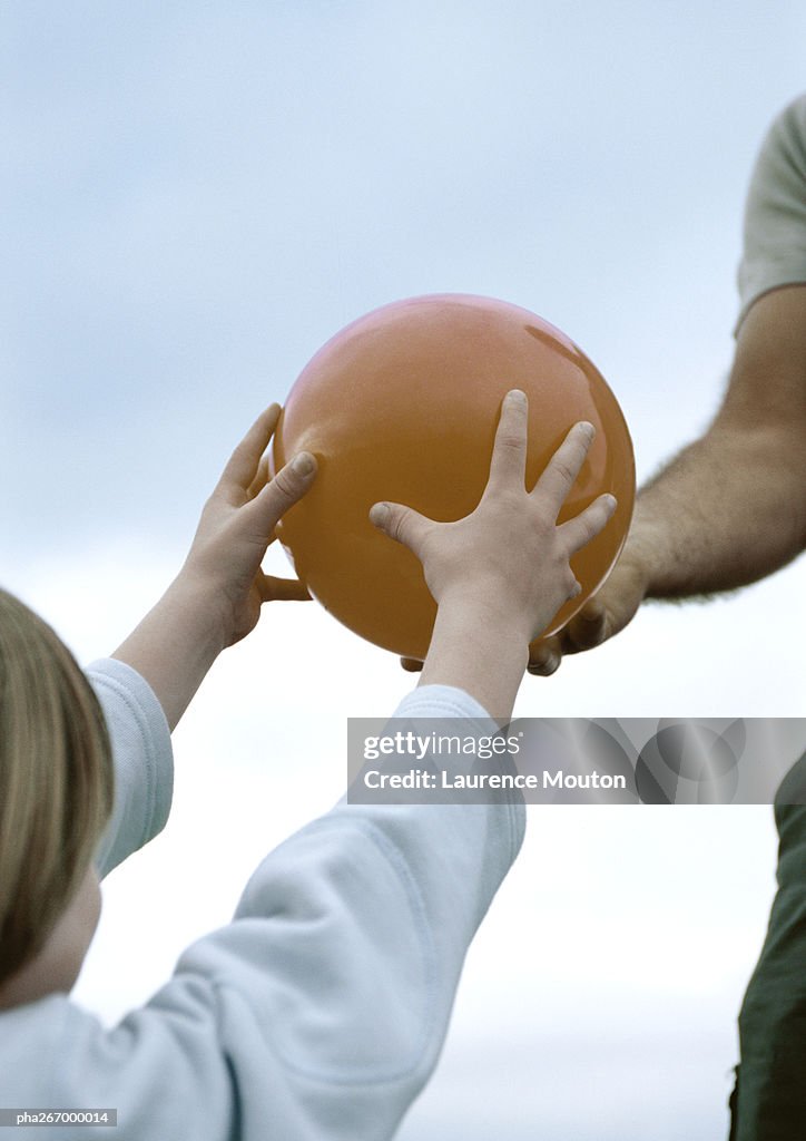 Boy taking ball from father, partial view