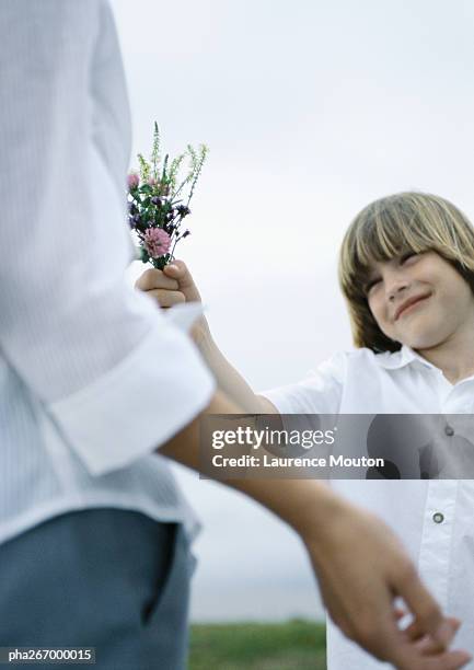 boy handing woman bouquet of wildflowers - entorno de flora fotografías e imágenes de stock