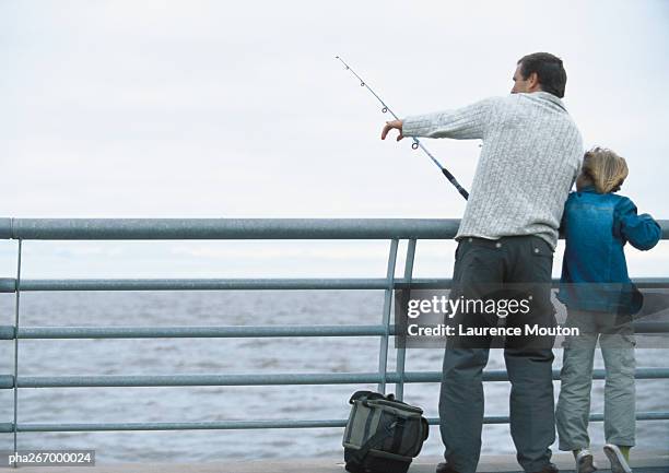 man and son fishing on pier, man pointing, full length - being watched stockfoto's en -beelden