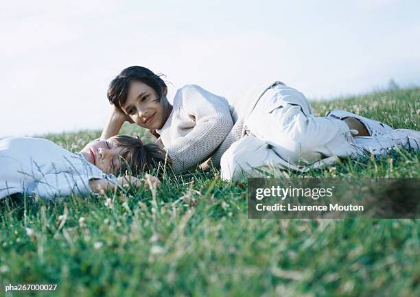 boy and girl lying on grass - happy tween girls lying on grass stock pictures, royalty-free photos & images