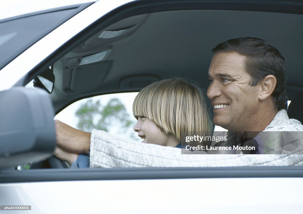 Man driving car with son on lap, side view