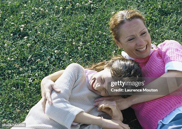 woman and daughter lying on grass laughing - happy tween girls lying on grass stock pictures, royalty-free photos & images