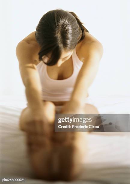 woman touching toes on bed - zehenspitzen berühren stock-fotos und bilder