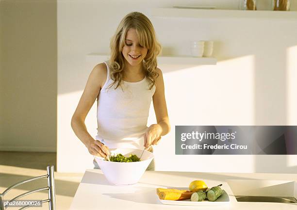 young woman preparing meal in kitchen - raw food diet stockfoto's en -beelden