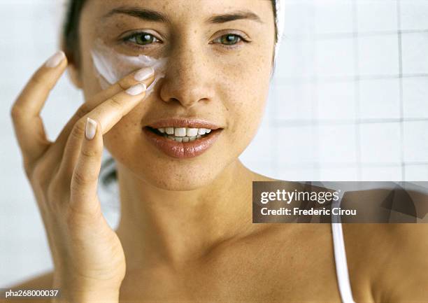 woman applying moisturizer beneath eye - cream stock pictures, royalty-free photos & images