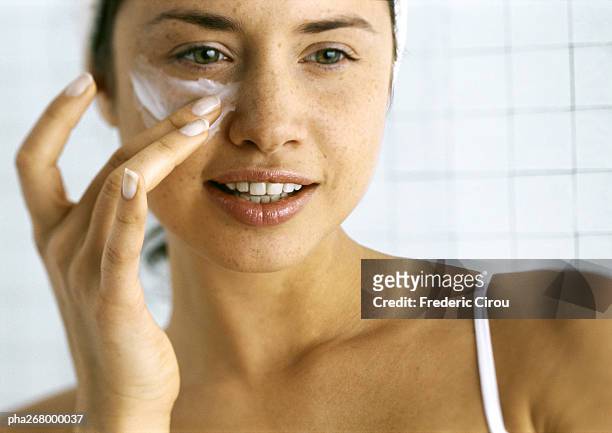 woman applying moisturizer beneath eye - applicera bildbanksfoton och bilder