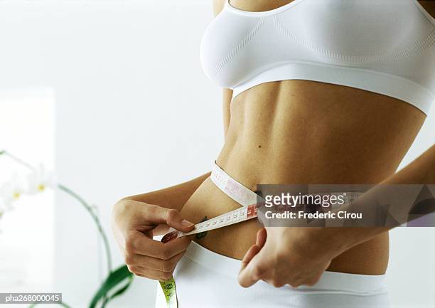 woman measuring waist, mid section - delgado fotografías e imágenes de stock