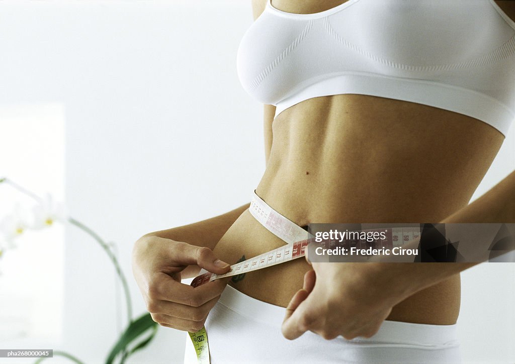 Woman measuring waist, mid section