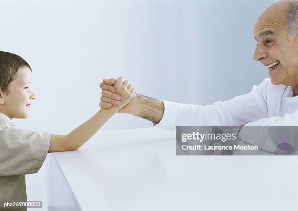 boy arm wrestling with grandfather - echar un pulso fotografías e imágenes de stock